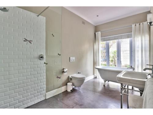 a bathroom with a tub and a toilet and a sink at The Good Host in Hout Bay