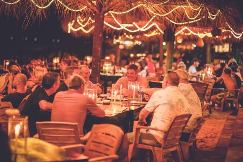 a group of people sitting at tables in a restaurant at Villa Paradise in Hikkaduwa