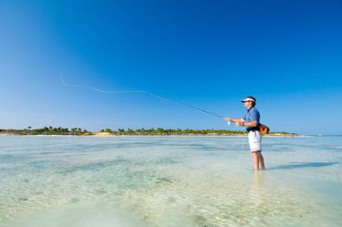 a man standing in the water flying a kite at Ambergris Cay - Private Island All-Inclusive in Big Ambergris Cay