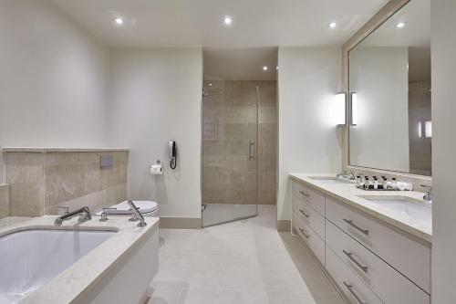 a bathroom with a tub, sink, mirror and bathtub at The Samling Hotel in Windermere