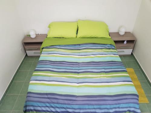a bed with a colorful striped blanket on the floor at Alifra Apartment in Lagun