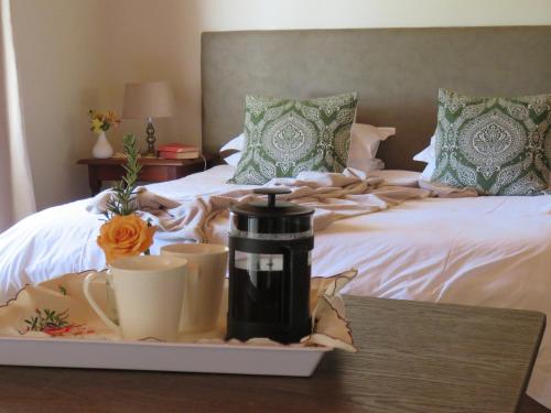 a tray with cups and a coffee maker on a bed at Modderkloof Farm Accommodation in Paarl