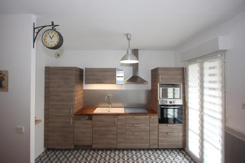 une cuisine avec un évier et une horloge murale dans l'établissement App 3 pièces hyper proche Disney, refait à neuf, à Serris