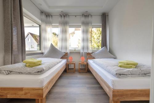 two beds in a room with two windows at Ferienapartments Zwingenberg in Zwingenberg