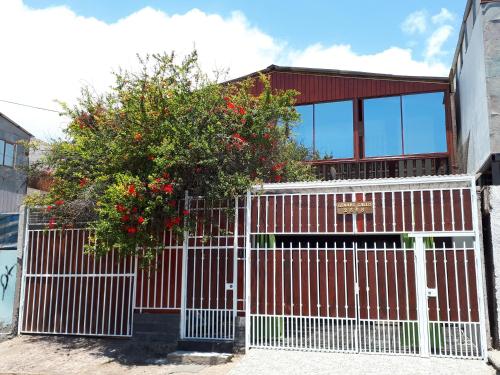 een wit hek met een boom voor een huis bij Casa Cely in Iquique