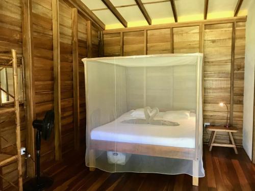 a bedroom with a bed in a wooden room at Casita del Mar- Caribbean Beachfront Bungalow in Chiquita Beach in Puerto Viejo