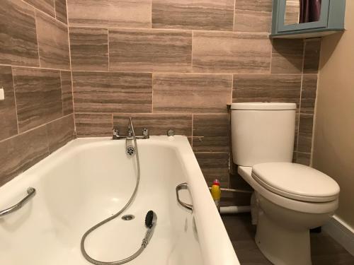 a bathroom with a toilet and a bath tub at 5 bed cottage in welsh valleys in Rhondda