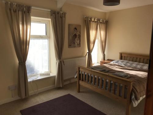 a bedroom with a bed and a window with curtains at 5 bed cottage in welsh valleys in Rhondda