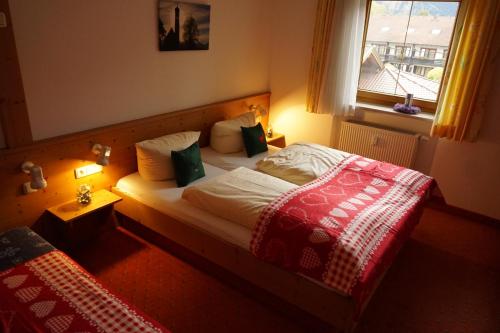 a bedroom with a bed with a red blanket and a window at Branderschrofen in Schwangau