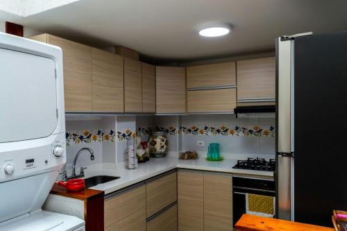 a kitchen with wooden cabinets and a black refrigerator at Elizabetha Hostal in Salento