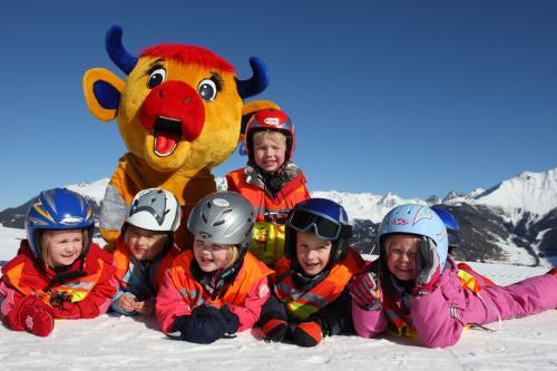 a group of children in the snow with a mascot at Telfeshof in Fiss