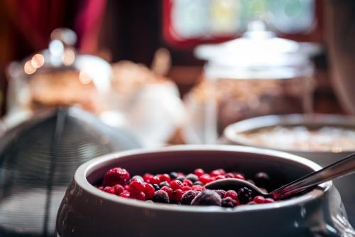 a bowl of berries with a spoon in it at Hôtel des Deux Clefs in Turckheim