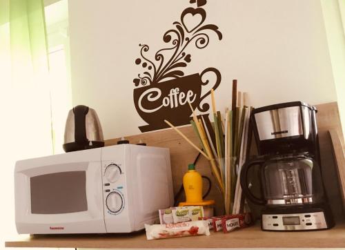 a kitchen counter with a microwave and a coffee sign at Kókusz Apartmanok in Eger