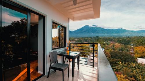 balcón con mesa, sillas y montaña en Kingswick Residences & Lodge, en Dumaguete