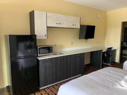 a kitchen with a black refrigerator and a microwave at HomeStay Inn & Suites Edinburg in Edinburg