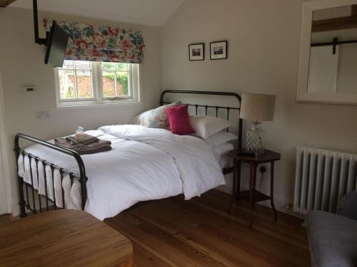 a bedroom with a bed with white sheets and pink pillows at The Parcel Shed in Gilling East