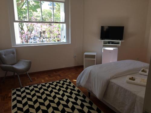 um quarto com uma cama, uma televisão e uma janela em Hotel Centenario Itajuba em Itajubá
