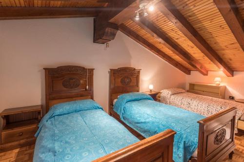 2 bedden in een slaapkamer met houten plafonds bij Maison Courthoud Alloggio ad uso turistico - VDA - RHÊMES-SAINT-GEORGES n 0002 in Rhemes-Saint-Georges