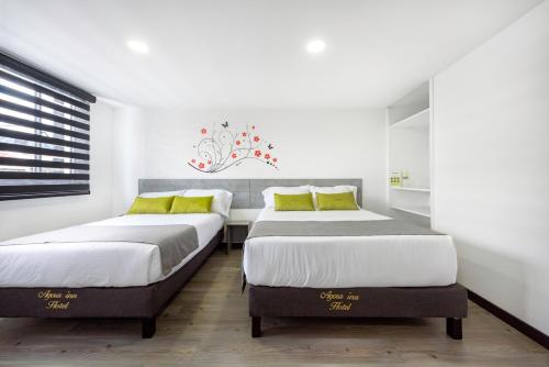 two beds in a bedroom with white walls and yellow pillows at Ayenda 1024 Agora Inn Hotel in Bogotá