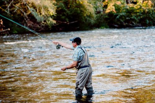 a man standing in a river holding a fishing rod at Cowichan River Lodge in Lake Cowichan