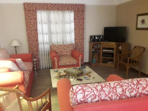 a living room with a couch and chairs and a tv at Hermosa Casa Cerca de Todo in Rosario