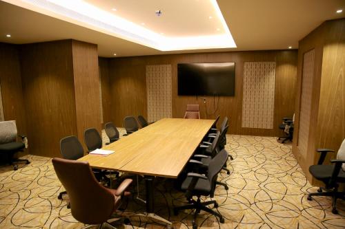 リヤドにあるQuetzal Aparthotelの大きな木製テーブルと椅子付きの会議室
