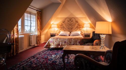 a bedroom with a large bed and a table at Hôtel des Deux Clefs in Turckheim