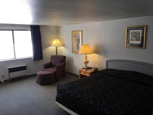 ein Hotelzimmer mit einem Bett, einem Stuhl und einem Fenster in der Unterkunft Americas Best Value Inn Billings in Billings