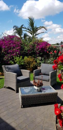 a patio with two chairs and a table and flowers at Oxford Rise Apartment in Bayswater