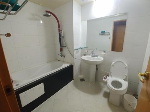 a bathroom with a sink and a toilet and a bath tub at New Grand Hotel in Daegu