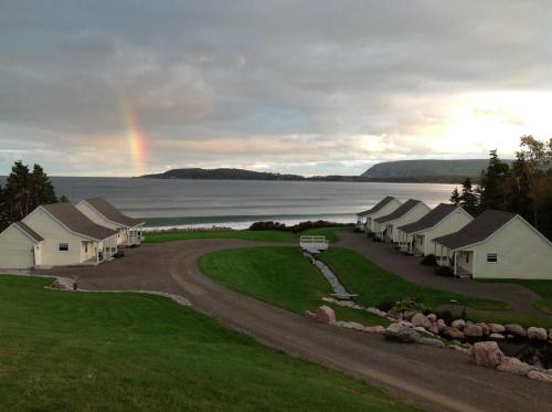a rainbow in the sky over a row of houses at Lantern Hill & Hollow in Ingonish Beach