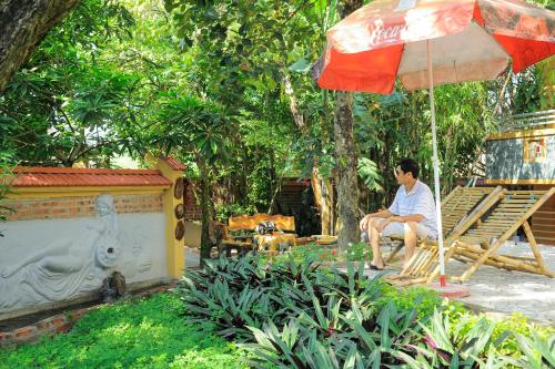 a man sitting on a chair under an umbrella at Hoang Giang Homestay in Ninh Binh