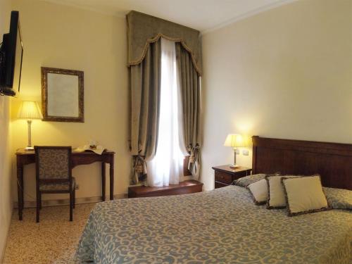 a bedroom with a bed and a chair and a window at Hotel Dell'Opera in Venice