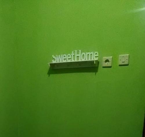a green wall with a sign that says synergy home on it at Kona backpaker syariah in Yogyakarta