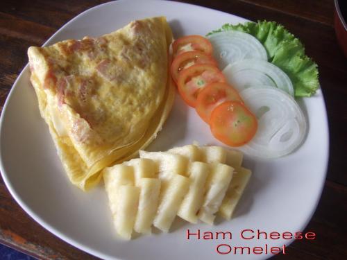 a white plate with a ham cheese omelet and a hot dog at TR Guesthouse in Sukhothai