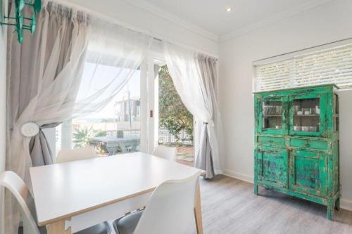 a dining room with a white table and a green cabinet at Rinkink Beach House in Wilderness