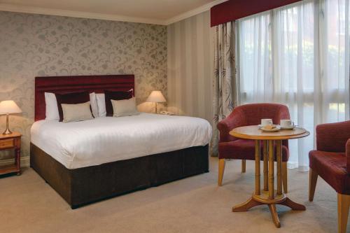 a bedroom with a bed and a table and a chair at Knights Hill Hotel & Spa in Kings Lynn