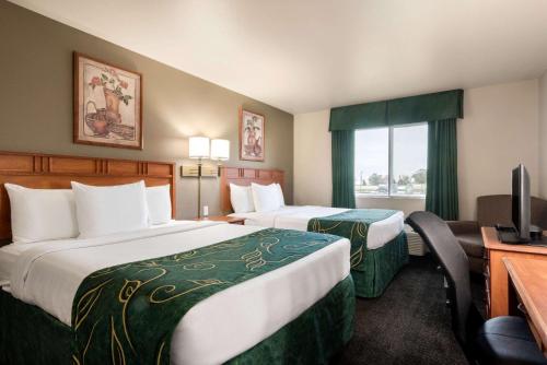 a hotel room with two beds and a desk and a television at Travelodge by Wyndham Missouri Valley in Missouri Valley
