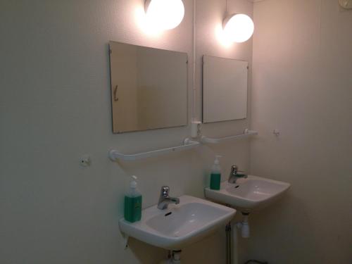 a bathroom with two sinks and two mirrors at Källviken Semesterby in Strömstad