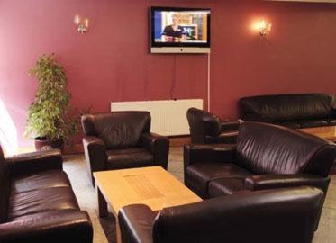 a waiting room with leather furniture and a tv at Parkside International Hotel in Reading
