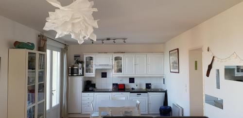 a kitchen with white cabinets and a chandelier at Le clapotis de l'Ô, calme, balcon sur la mer, à 2 h de Paris in Ault