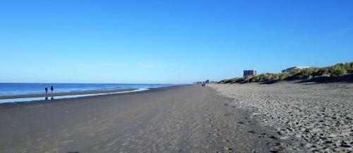 a beach with people walking on the sand and the ocean at Florentinus met hottub, afgesloten tuin en overdekt terras in Veurne