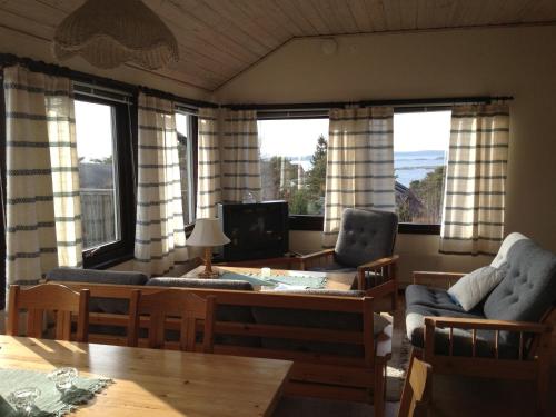 a living room with a table and chairs and windows at Källviken Semesterby in Strömstad