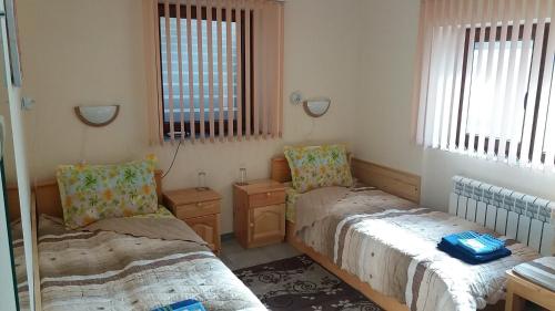 two beds in a room with two windows at Нощувки Ботеви in Shumen