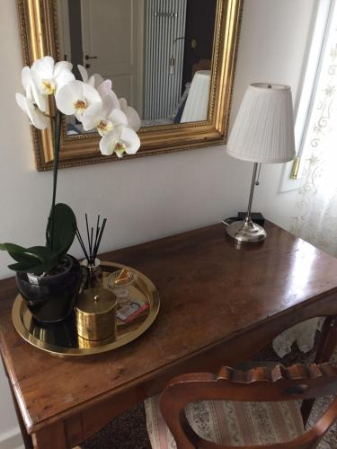a table with a mirror and a vase of flowers on it at B&B Colombo by Addler House Ospitality in Mestre