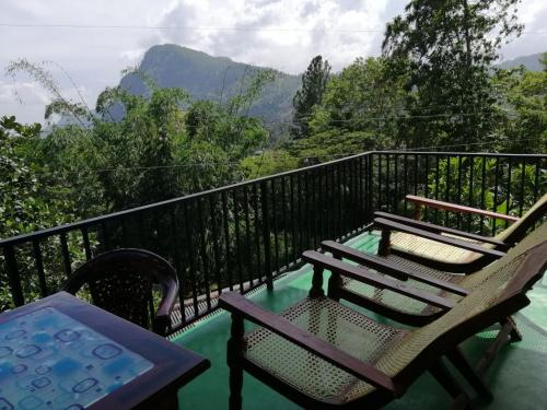 d'un balcon avec une table, des chaises et des montagnes en arrière-plan. dans l'établissement Little paradise Homestay, à Ella