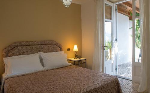 a bedroom with a bed next to a sliding glass door at Hotel Villa Enrica - Aeolian Charme in Lipari