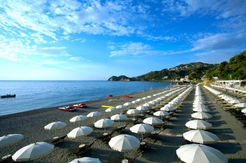 a beach with white umbrellas and the water at Hotel Isabella in Taormina