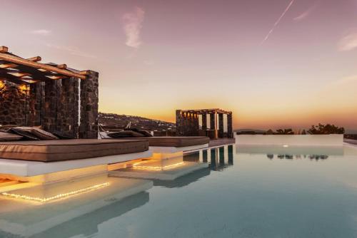 een hotelzwembad met een zonsondergang op de achtergrond bij Saint Apostles Villas in Fira