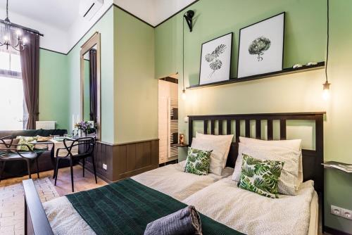 ブダペストにあるThe Green - elegant studio apartment in the center of Budapestの緑の壁のベッドルーム(ベッド1台、テーブル付)